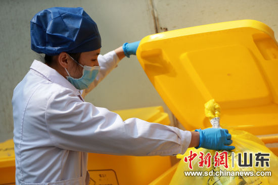 工作人员严格按照操作规范，将脱下的防护服封口、贴标签，装入医疗废物垃圾桶，等待转运车辆集中处理。梁?  摄