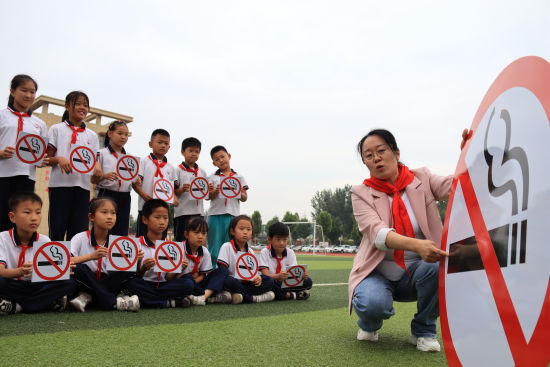 5月30日，在山东省聊城市茌平区胡屯镇胡屯小学，志愿者为孩子讲解禁烟知识。