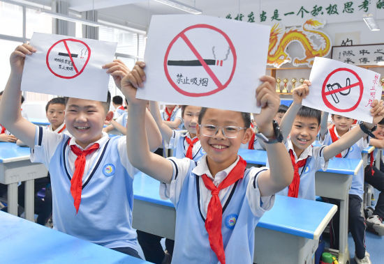 5月30日，在山东省临沂金雀山小学，学生们在展示画的禁烟标识