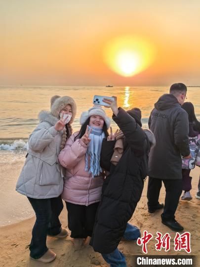 1月1日，山东日照，市民游客与2025年的第一缕阳光合影留念。苏雪 摄